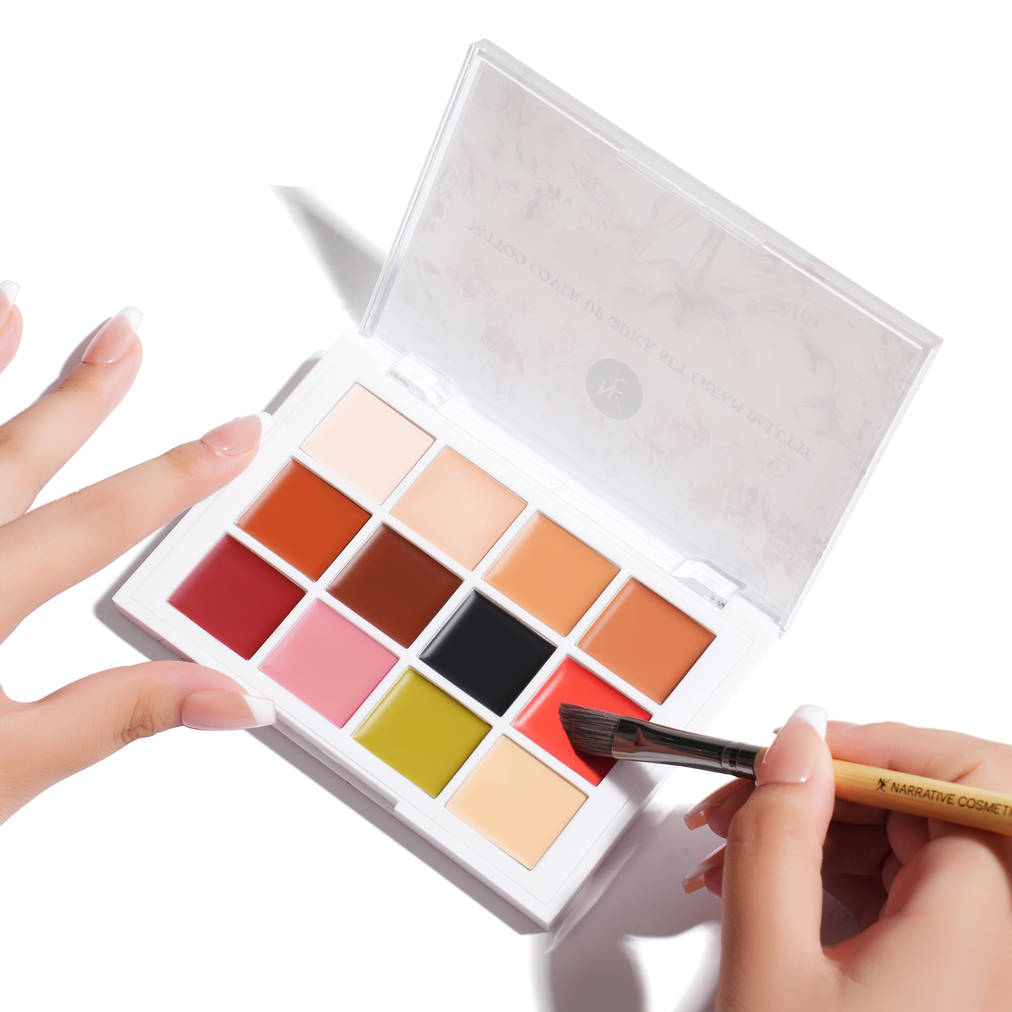 Hand applying brush to Quick-Set Tattoo Cover-Up Cream Palette in use